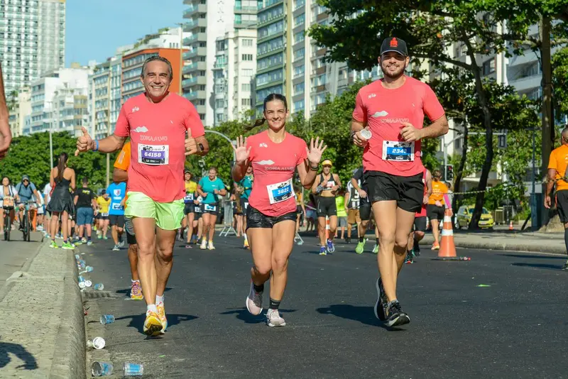 Corredores com camisetas coral em prova na orla