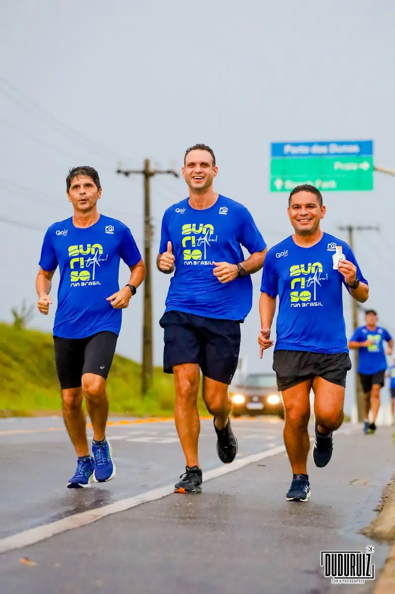 Três corredores com camisetas azuis da corrida Sunrise Run