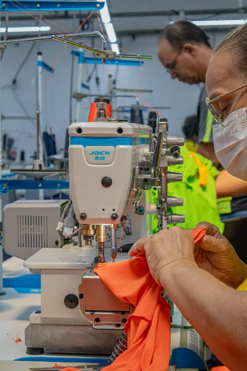 Costureira operando máquina no setor de costura da fábrica