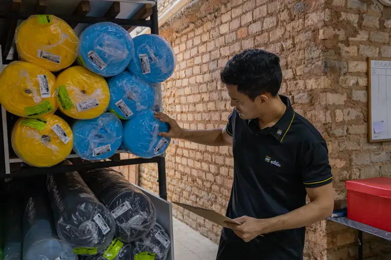 Colaborador no estoque de rolos de tecido da fábrica